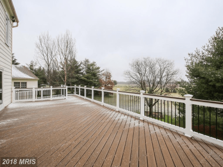 Enormous wood paneled deck with white fencing.