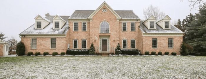 Multi-story brick home on a huge yard dusted with snow.